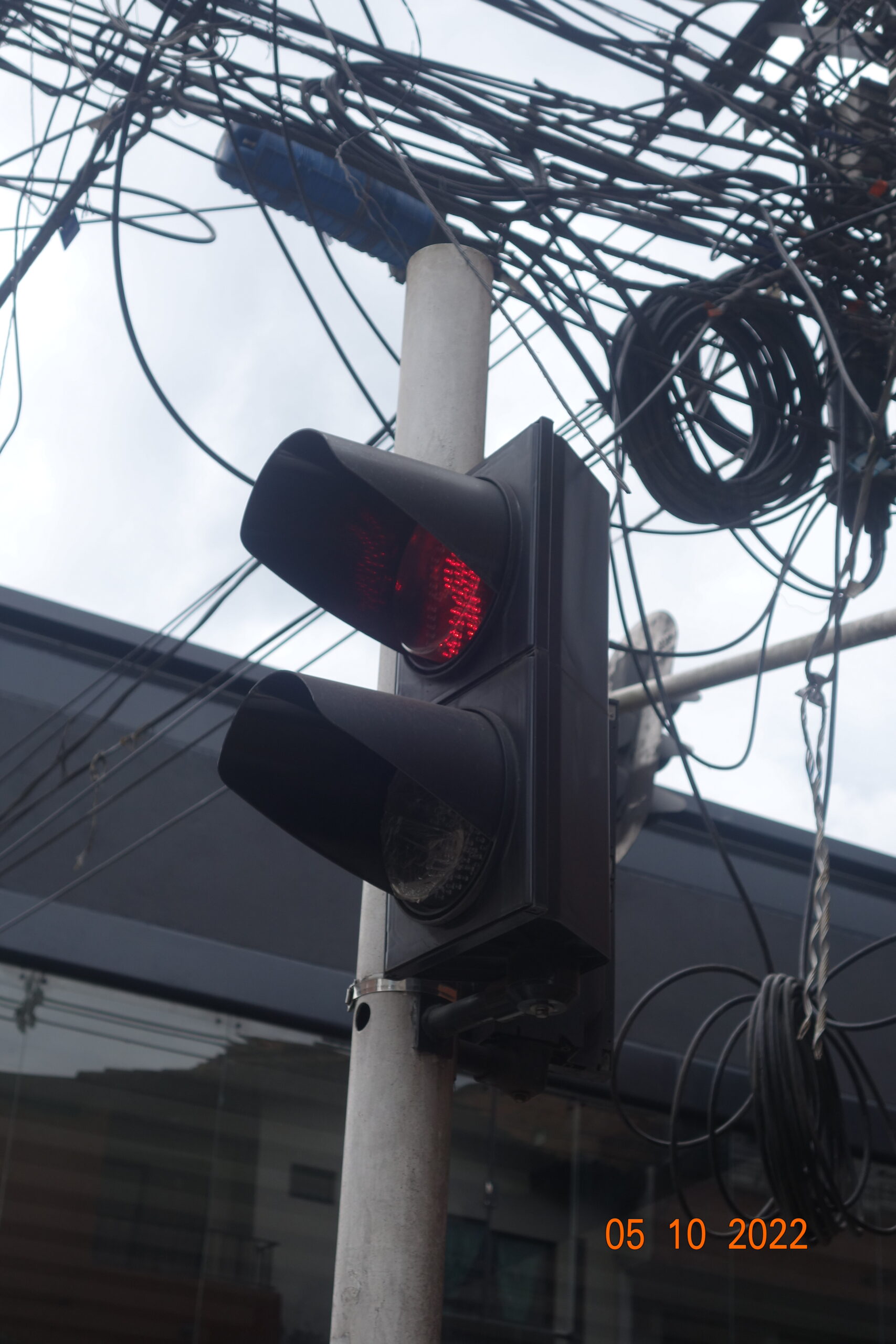 Primer plano de semáforo LED rojo en poste metálico con cables aéreos reorganizados, después de intervención técnica en Caldas.