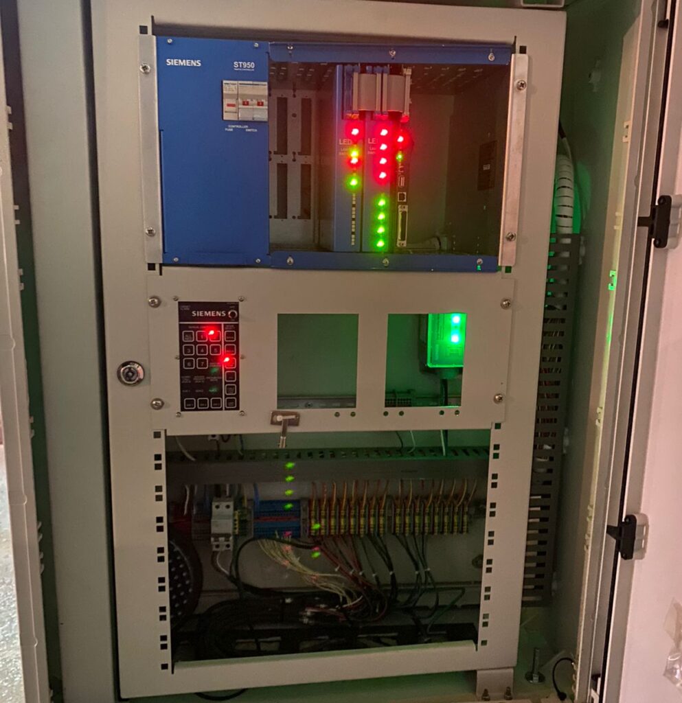 Interior del gabinete mostrando controlador electrónico Siemens ST950, tarjetas de salida, LEDs de estado y cableado organizado para la red semafórica de Tunja.
