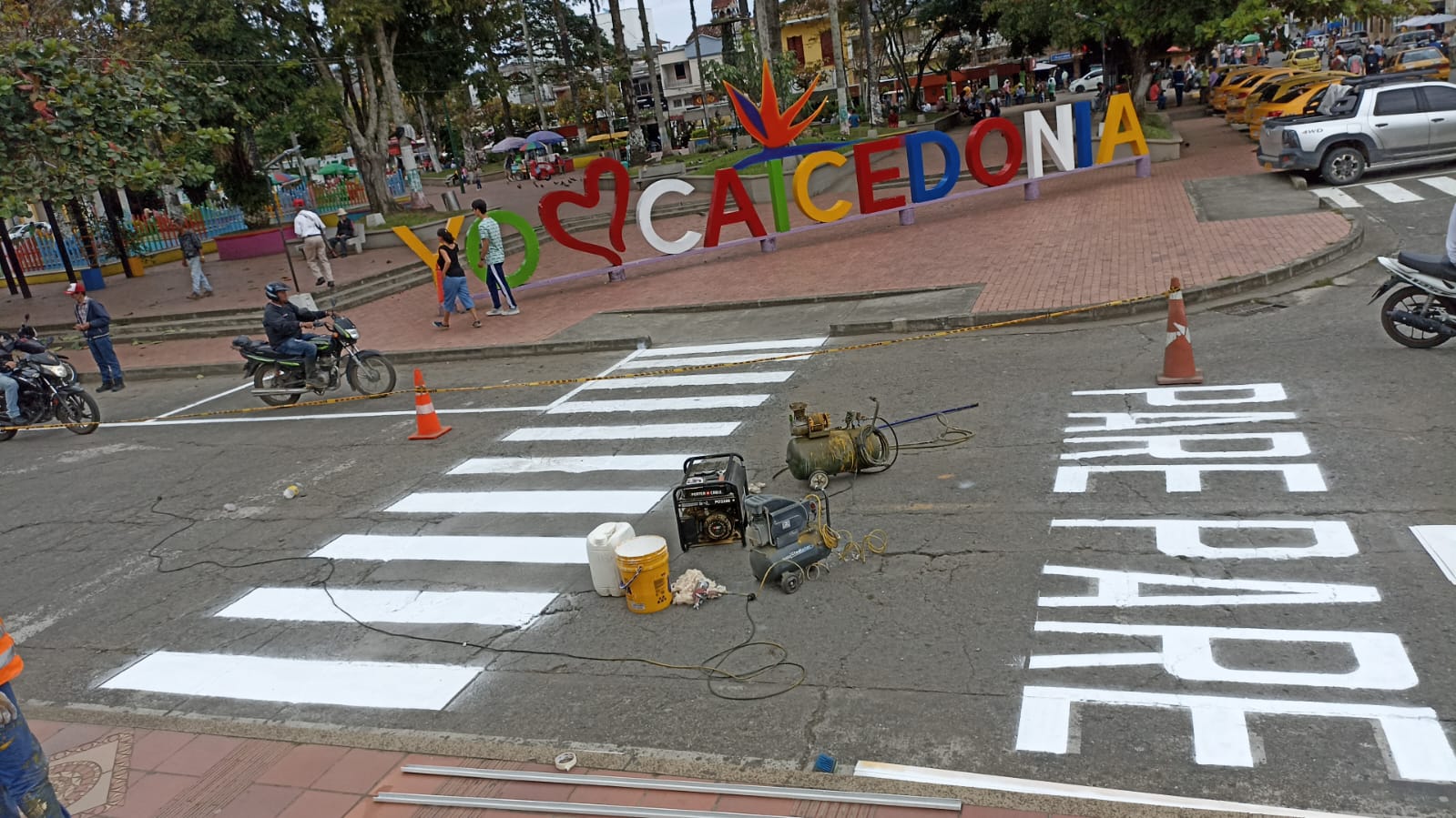 Obreros de Smart Planning pintan paso peatonal y texto “PEATONAL” con pintura acrílica frente al parque YO ❤️ CAICEDONIA.