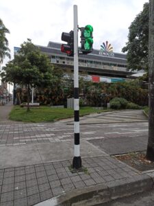 Semáforo peatonal con cronómetro verde frente al centro comercial Victoria en Pereira, con tachas viales y delineadores instalados en la calzada.
