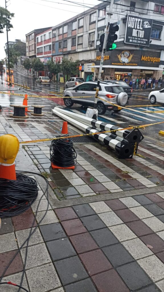 Conos naranjas y boyas metálicas amarillas apiladas en acera, junto a cables listos para señalización vial en Pereira.