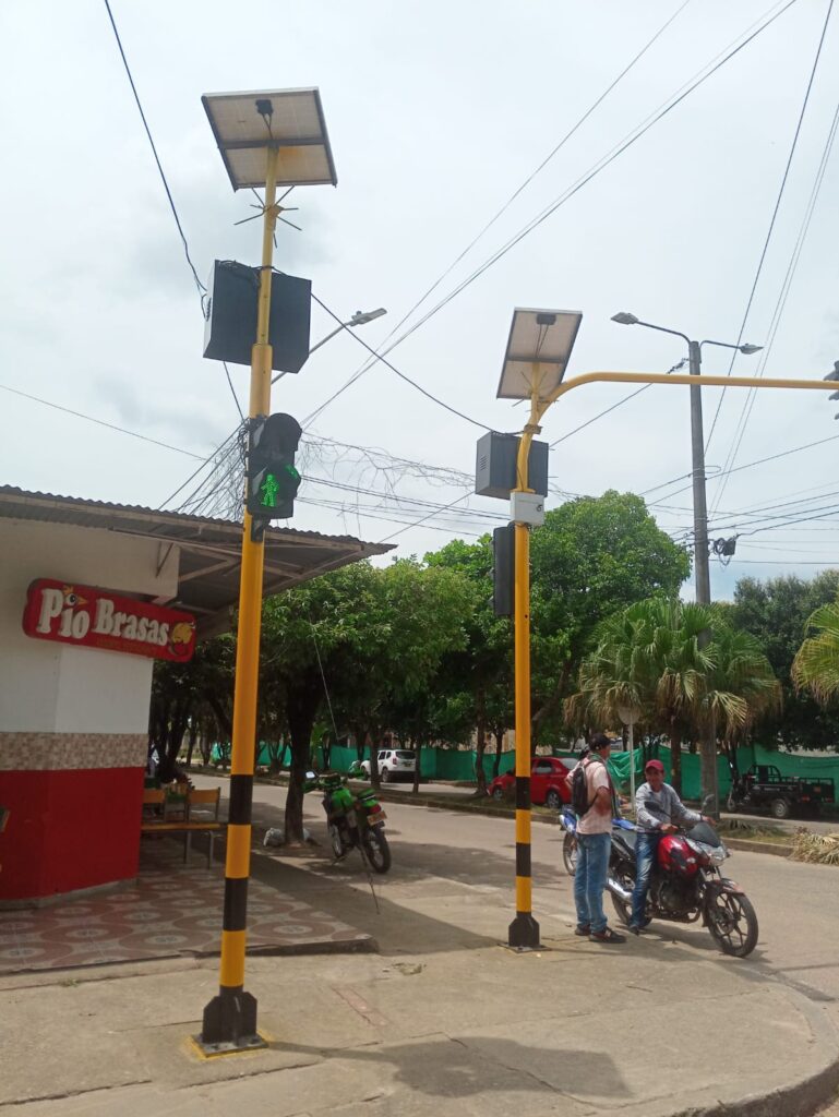 Dos postes con semáforos vehiculares y peatonales, control adaptativo y paneles solares, en la intersección de Av. Carrera 23 con Av. Sierra Nevada.