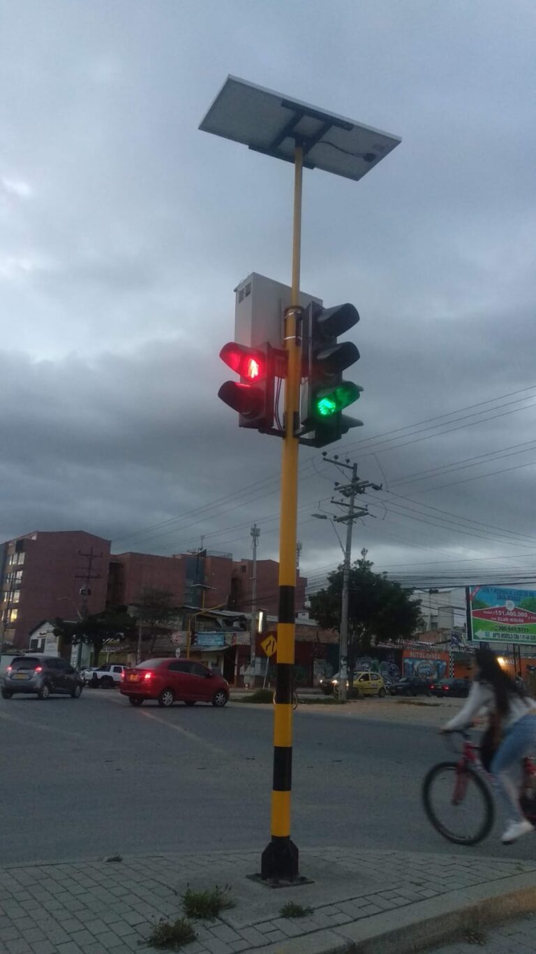 Semáforo con luz verde y roja, alimentado por módulo solar, instalado en intersección de Madrid.
