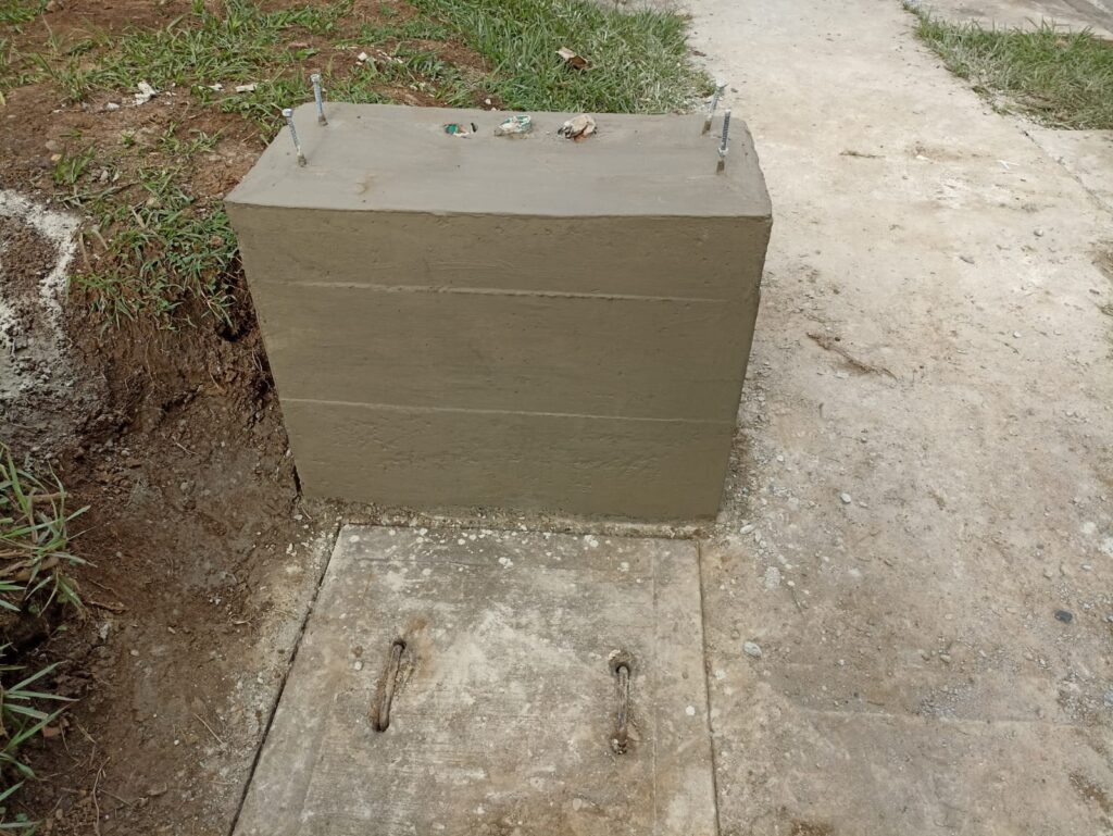 Cimentación de concreto recién vaciada con pernos de anclaje para gabinete eléctrico de la red semafórica en Santiago de Cali.