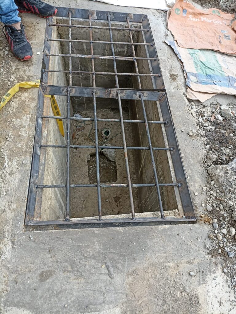 Rejilla y marco de acero instalados sobre cámara de paso de cables semafóricos durante obras civiles en Santiago de Cali.