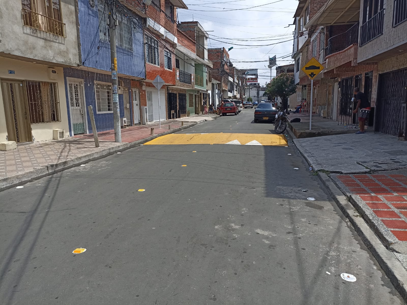 Calle residencial con reductor amarillo, flechas blancas y tachas reflectivas, más señal vertical de loma en Santiago de Cali.