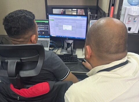 Técnicos ajustando la configuración de los terminales de huella y reconocimiento facial en un escritorio con monitores.