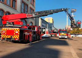 Camión de bomberos con escalera hidráulica extendida durante maniobras en el edificio de bomberos de Bucaramanga.
